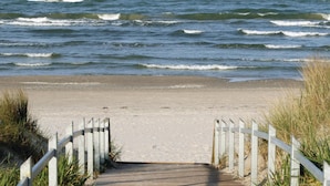 A wooden pathway leading to a sandy beach with waves in the background. - Baltic (Binz)