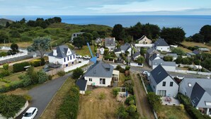 A residential area with houses, a road, and a view of the sea. - Vacation home, 400m from the sea in a quiet, well-located area (Saint-Quay-Portrieux)
