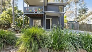 Una casa de dos pisos con un balcón, rodeada de vegetación y árboles.