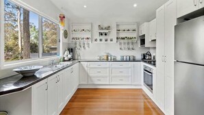 Una cocina moderna con armarios blancos, un refrigerador de acero inoxidable y piso de madera.