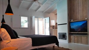 A modern bedroom with a bed, a television, and a ceiling fan. - Kaolin Rocabella Apartment with Private Sandy Pool (El Chorro)