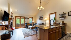 A spacious kitchen with wooden cabinets, a central island, and a dining area with a sofa and coffee table. - Close to Gondola and Short Walk to Keystone Base Area Shops and Dining! (Keystone)