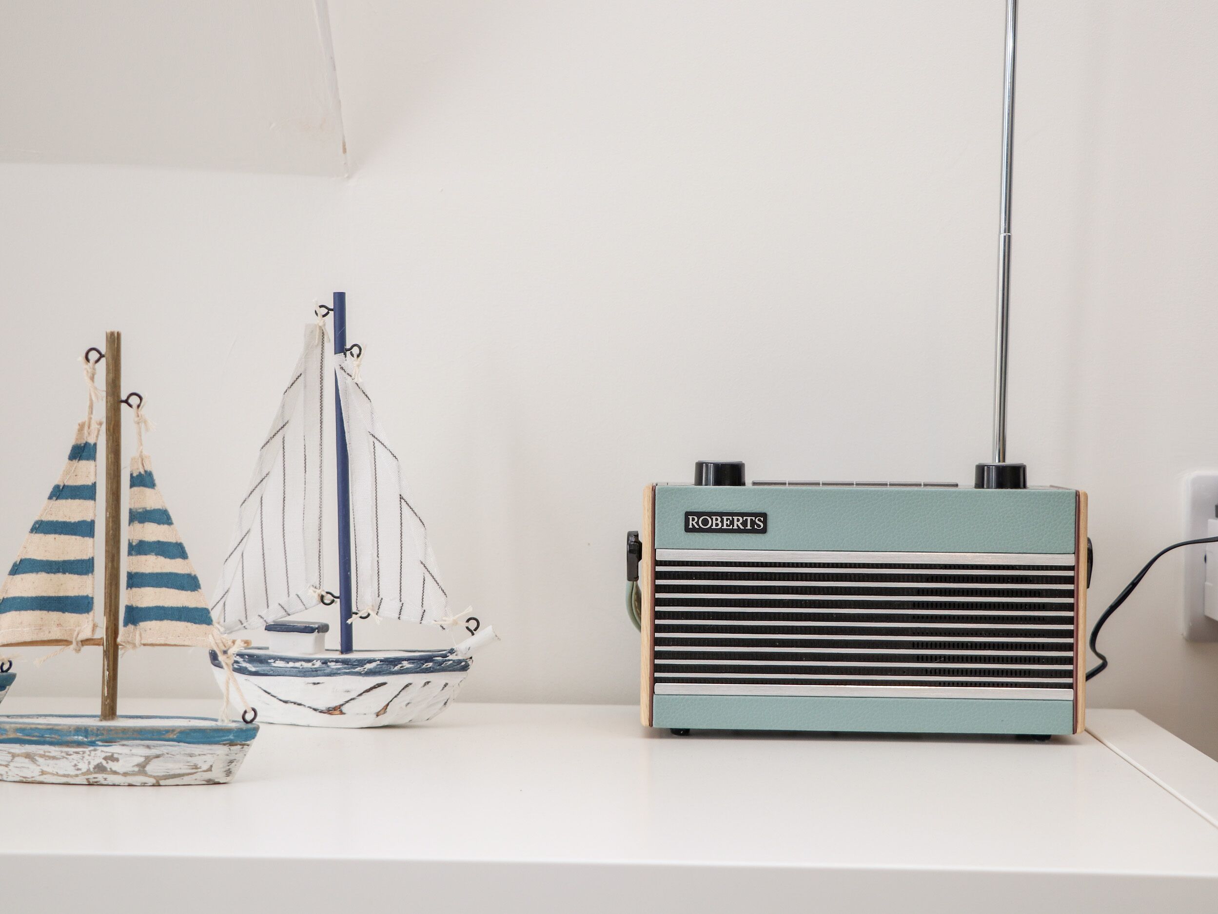 A vintage radio and two model sailboats on a white surface.
