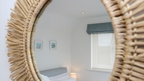 A bedroom with a bed, a bedside lamp, and two framed pictures on the wall. - Marazion Attic (Marazion)