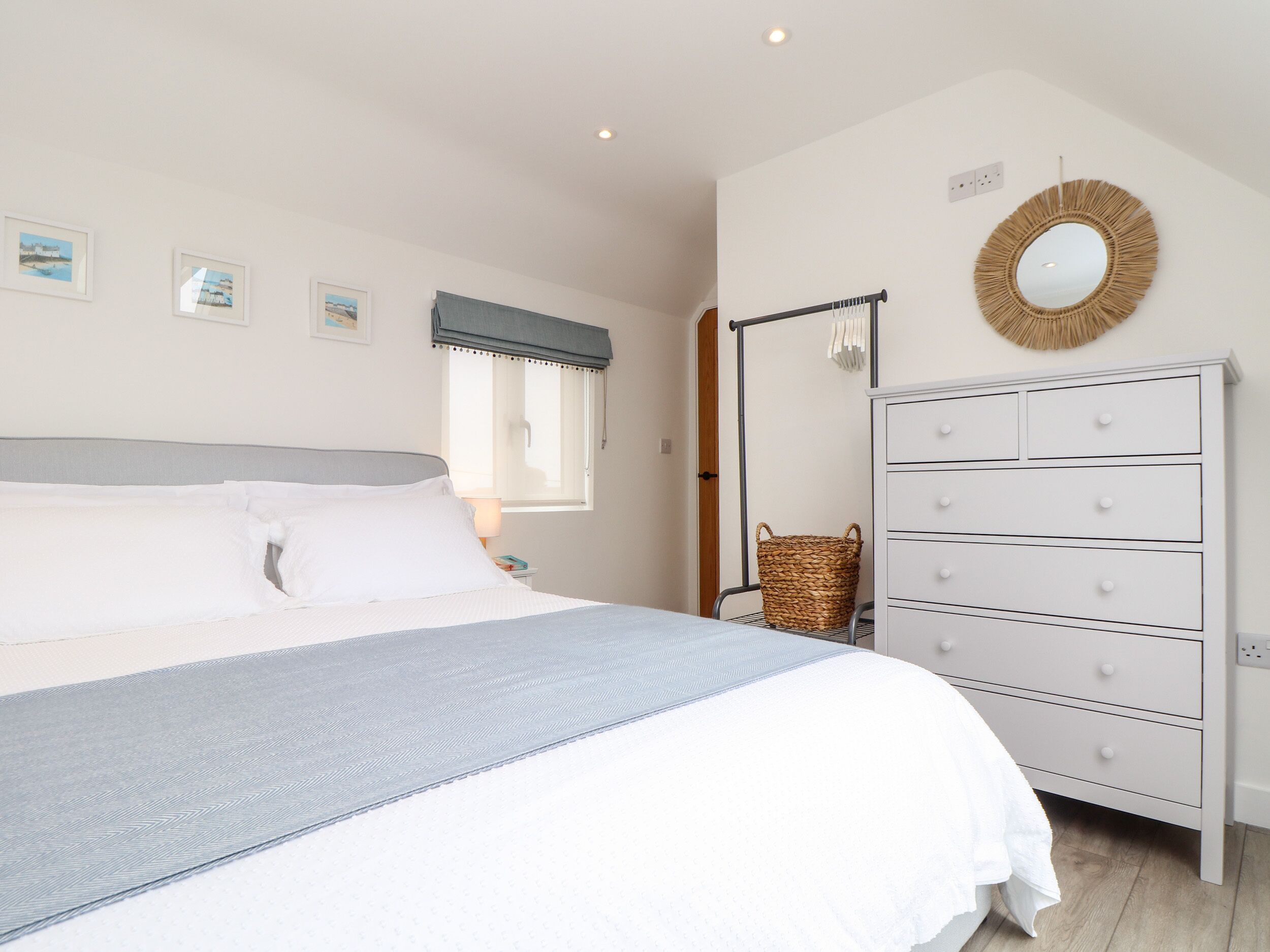 A bedroom with a bed, a dresser, a window with a view, and a wall-mounted mirror.