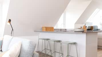 A modern kitchen with a central island, bar stools, and a dining area with a sofa.