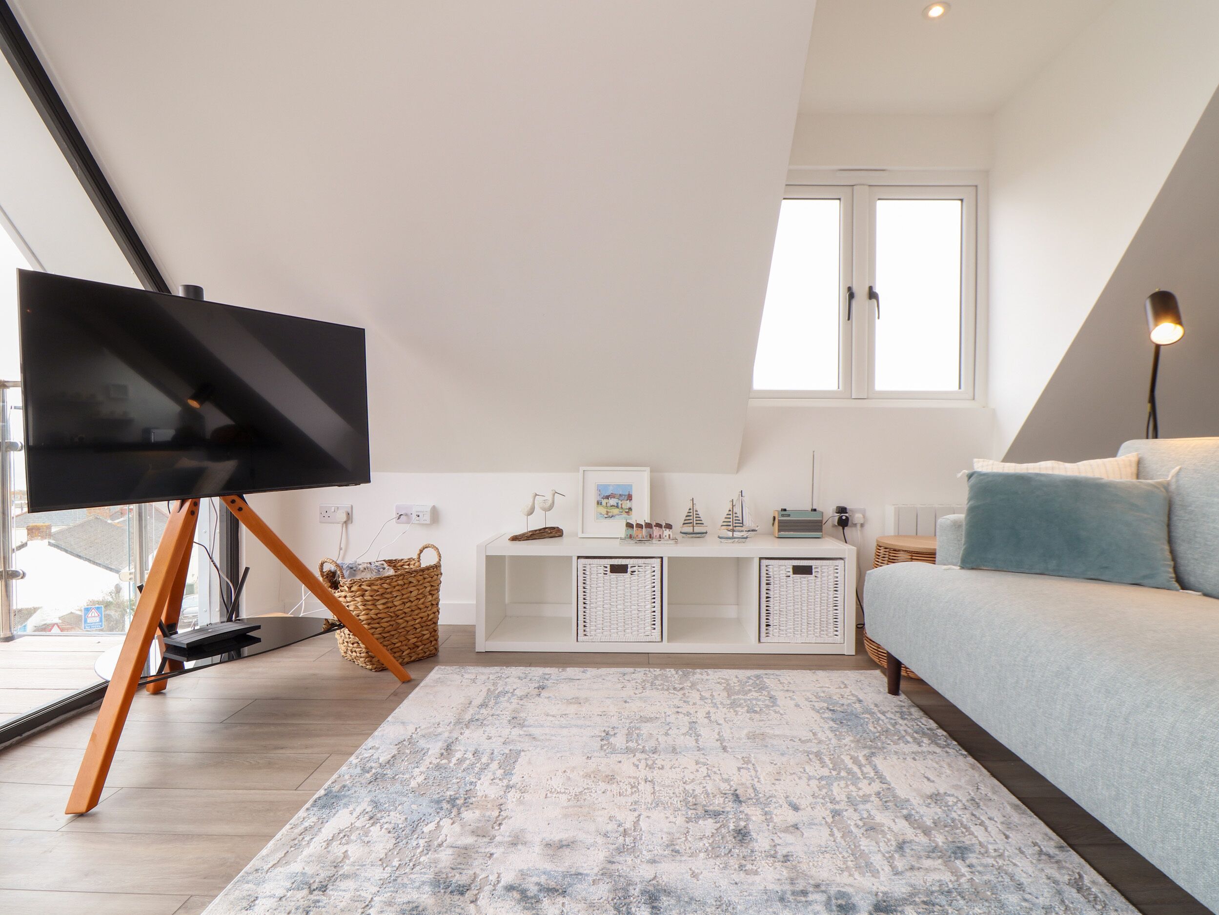 A modern living room with a television on a stand, a sofa, a coffee table, and a large window.