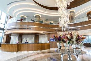 A modern hotel lobby with a curved reception desk, a large chandelier, and a glass railing overlooking the lower level. - La Quinta by Wyndham Istanbul Gunesli (Istanbul)