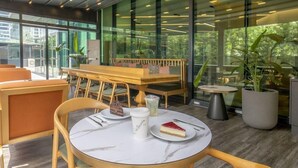 A modern indoor seating area with round tables, wooden chairs, and a bench. - La Quinta by Wyndham Istanbul Gunesli (Istanbul)