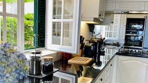 Una cocina moderna con armarios blancos, encimera negra y vistas al exterior.
