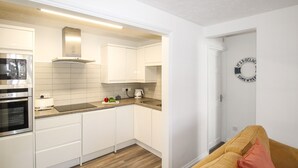 Une cuisine moderne avec des meubles blancs, un four à micro-ondes et une machine à café.