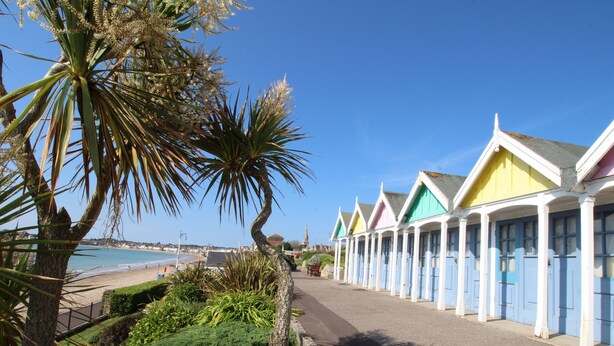 Une rangée de charmantes maisons de vacances colorées, situées en bord de mer et offrant une vue sur la plage.