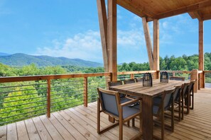 A wooden deck with a table and chairs, overlooking a mountainous landscape. - Mountain View Manor  ~ Mountain Modern 5BR ~ Near downtown Blue Ridge! (Blue Ridge)
