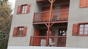 Un edificio a più piani con balconi, persiane in legno e una facciata bianca.