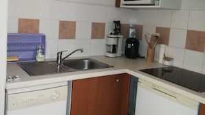 Una cucina compatta con lavello, forno a microonde, macchina del caffè e lavastoviglie.