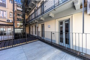 A multi-story residential building with balconies, a tiled ground floor, and a door with a window. - Italianway - The B Village Superior (Milan)