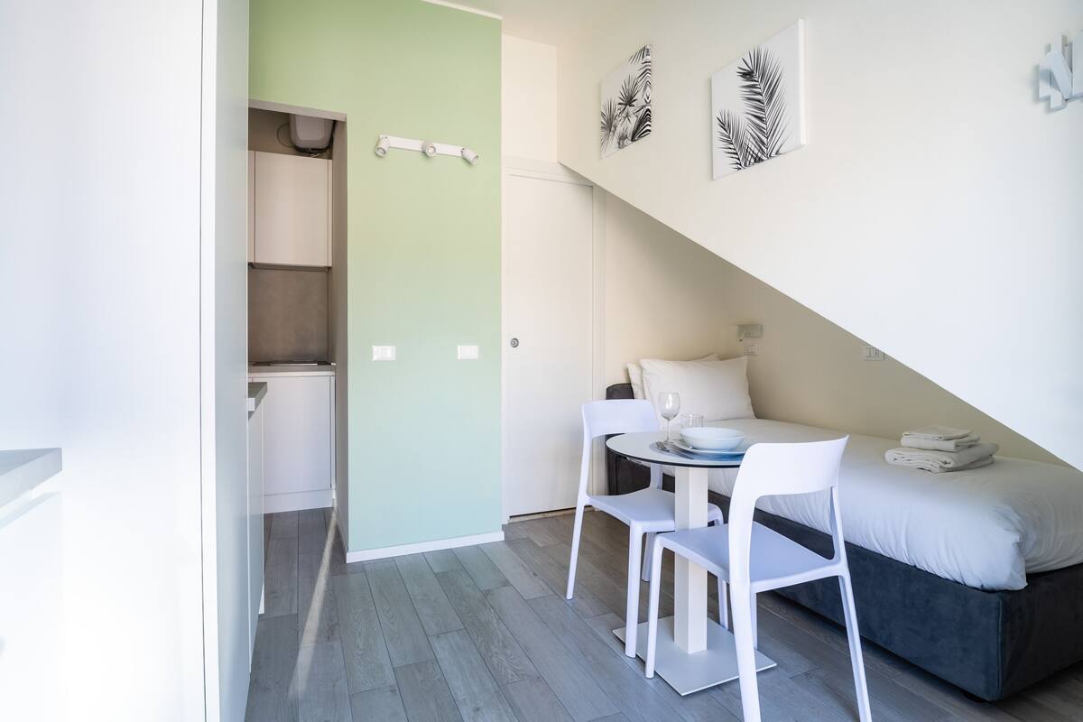 A compact, modern room with a dining area, a bed, and a kitchenette.