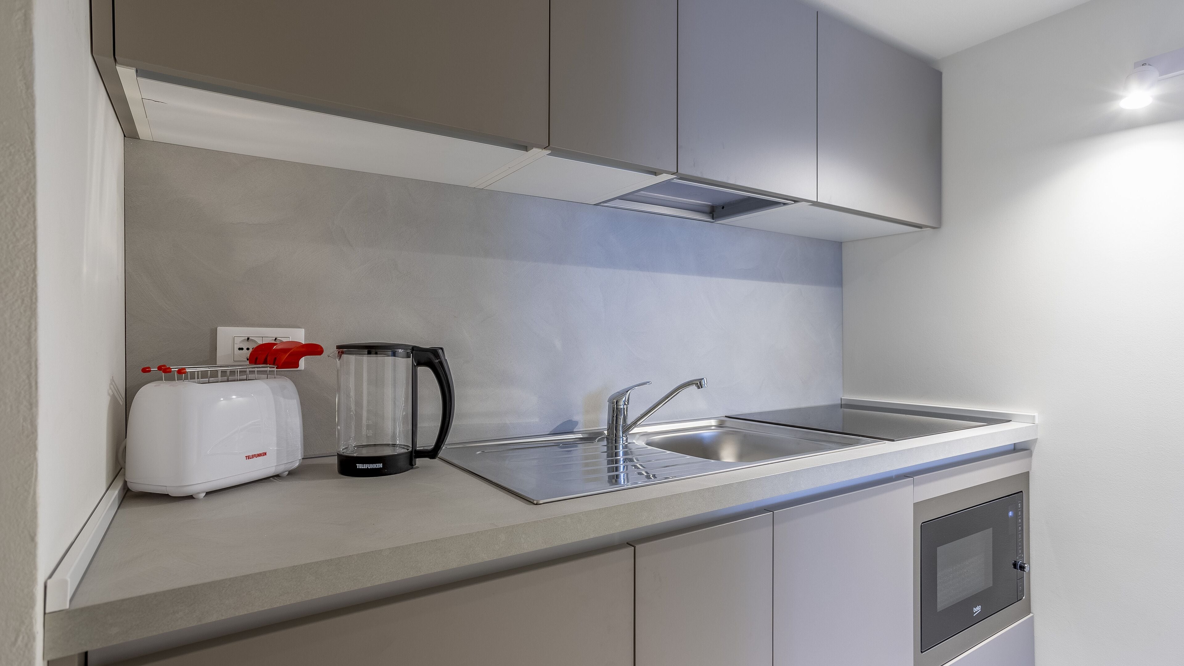A compact kitchenette with a toaster, kettle, and a microwave.