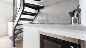A modern kitchen with a built-in dishwasher, a stainless steel sink, and a black staircase. - Italianway - The B Village Superior (Milan)