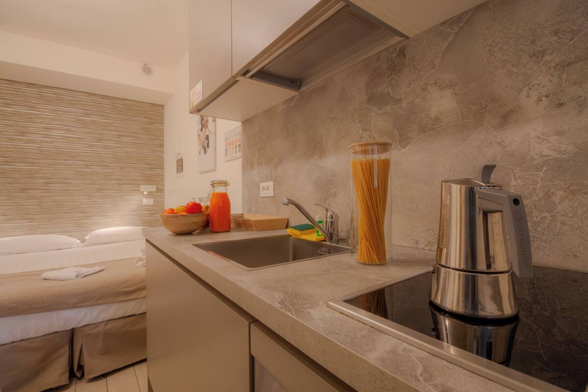 A modern kitchen with a built-in sink, a coffee maker, and a bowl of fruit on the counter.