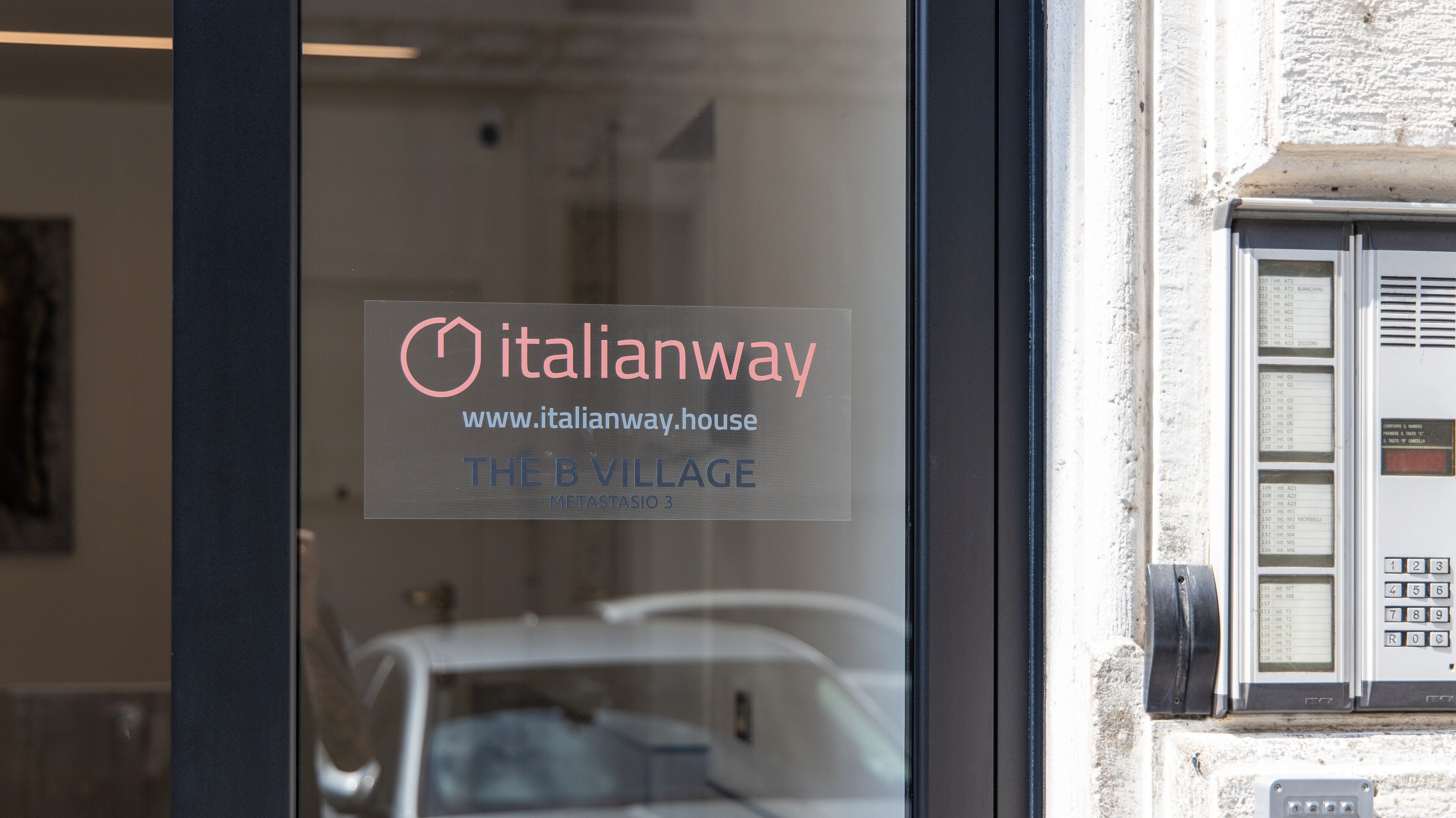 Eine Glastür mit dem Logo und dem Namen Italianway, das auf ein Hotel oder eine Unterkunft hinweist.
