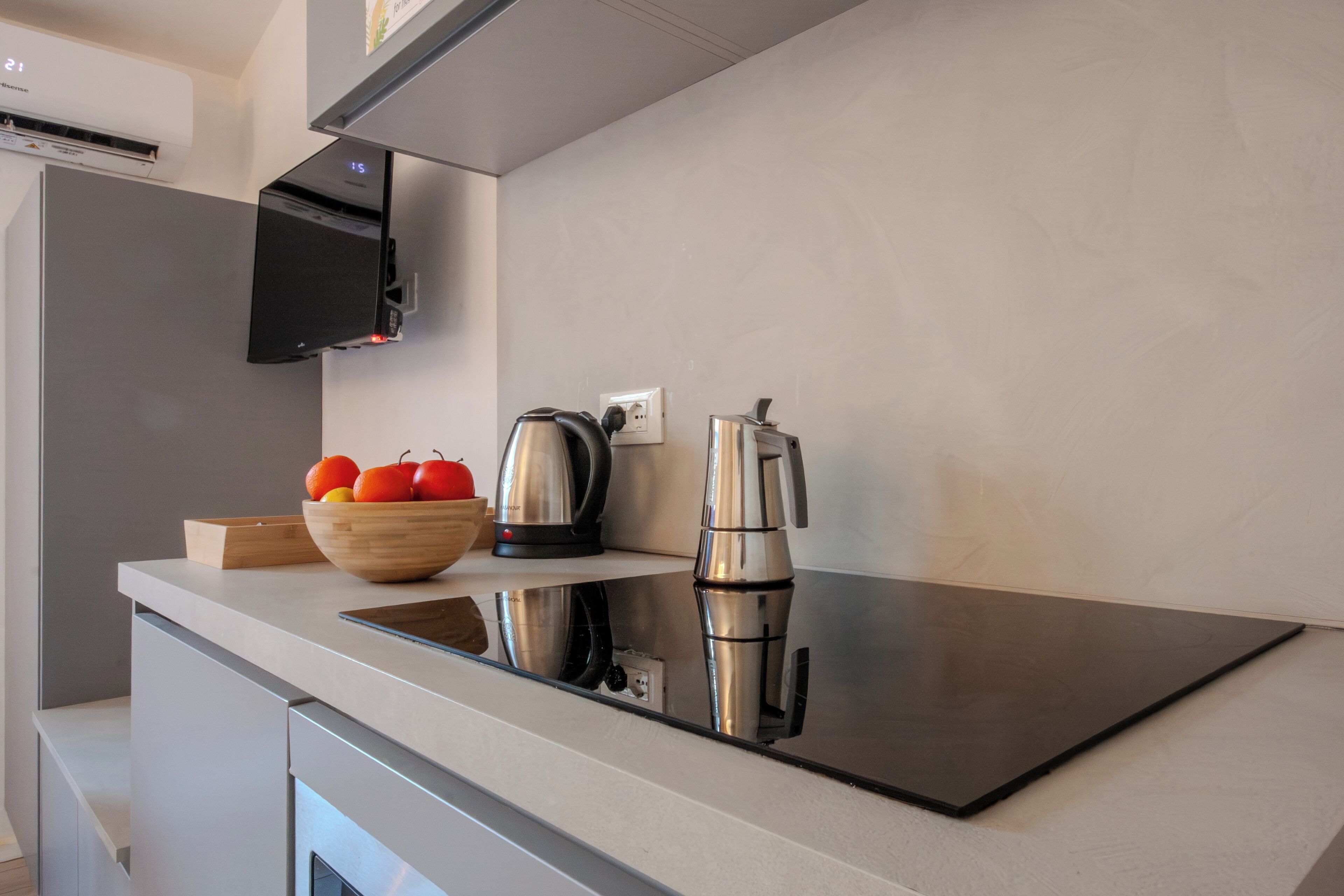 Une cuisine moderne dotée d’un élégant plan de travail noir, d’appareils électroménagers en acier inoxydable et d’un saladier en bois rempli de fruits.