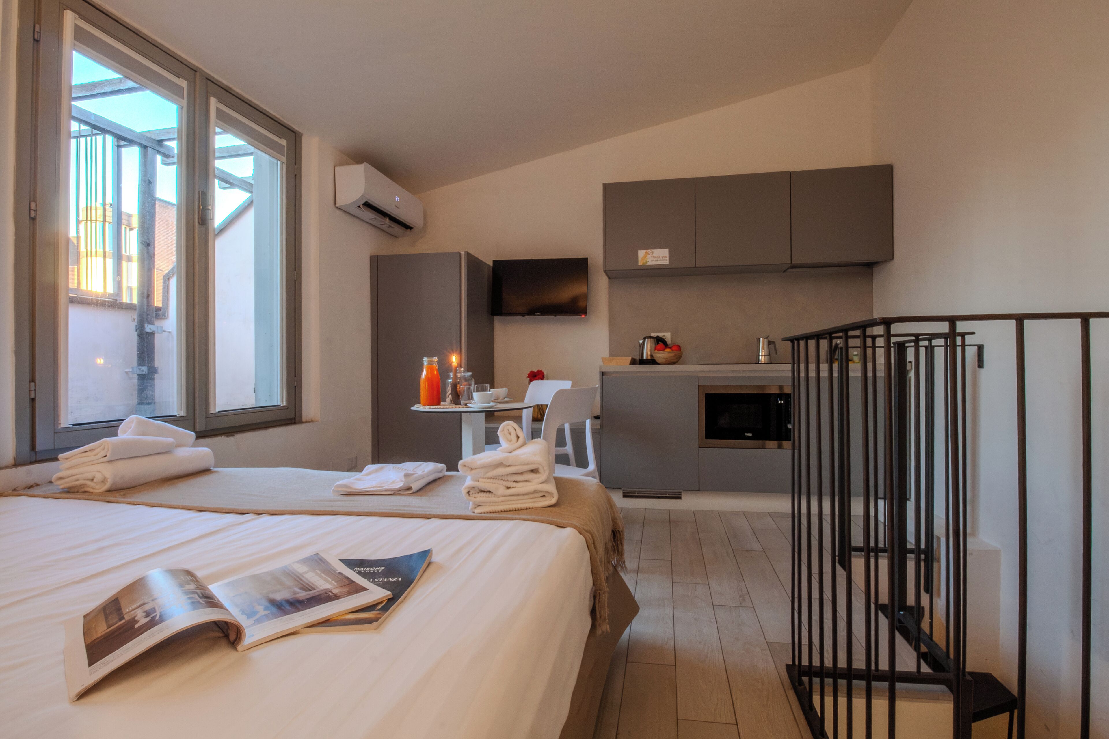 Une chambre d’hôtel comprenant un lit, une petite kitchenette, un coin repas et un balcon.