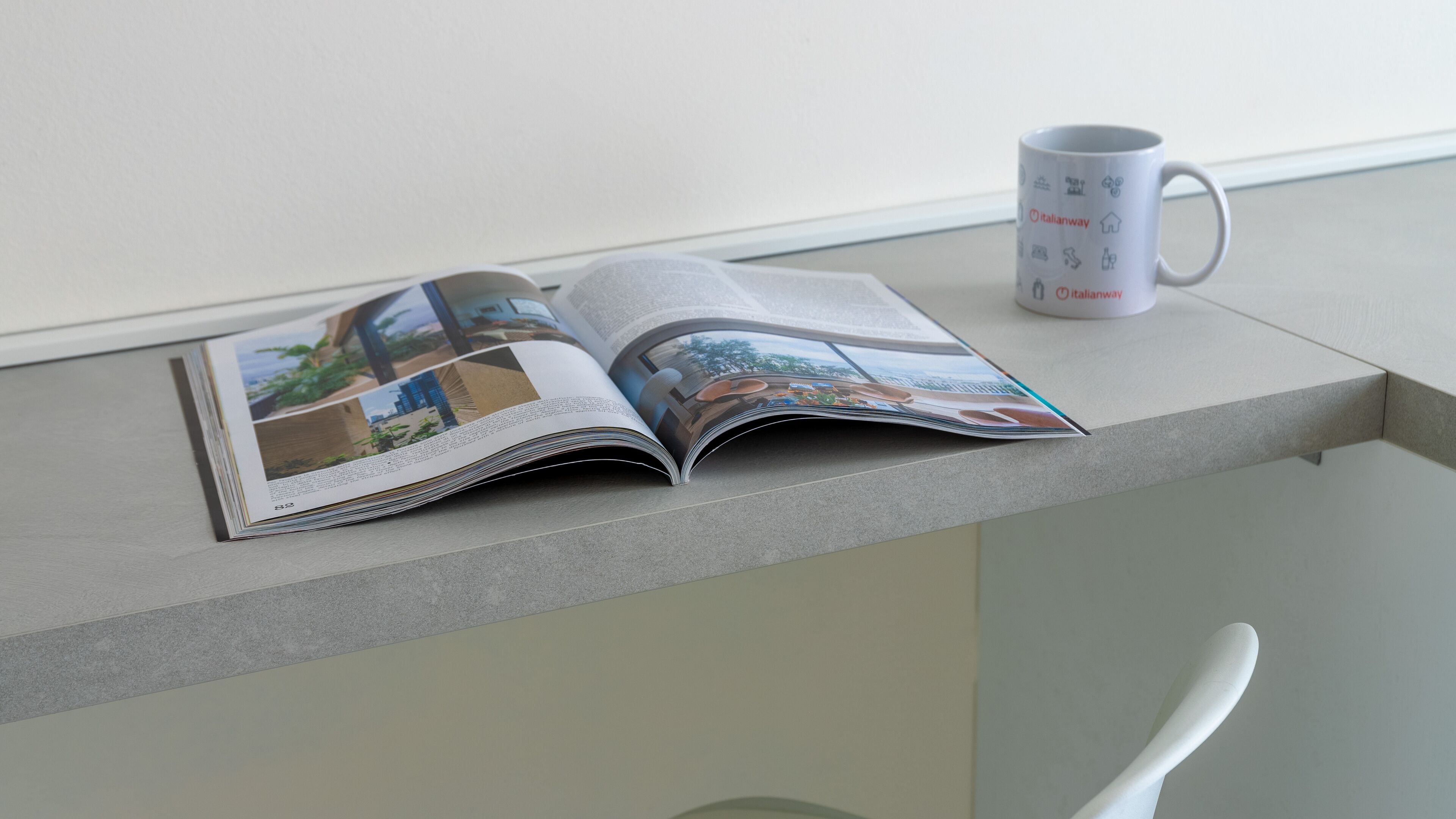 An open magazine on a table with a coffee mug beside it.