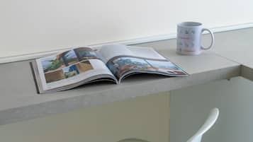 An open magazine on a table with a coffee mug beside it.