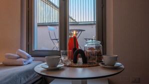 A room with a bed, a round table with a cup, a glass, and a bottle. - Italianway - The B Village Superior (Milan)