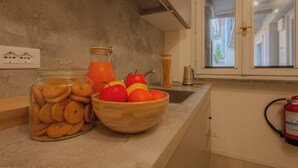 A kitchen with a wooden bowl of fruit, a jar of cookies, and a fire extinguisher mounted on the wall. - Italianway - The B Village Superior (Milan)