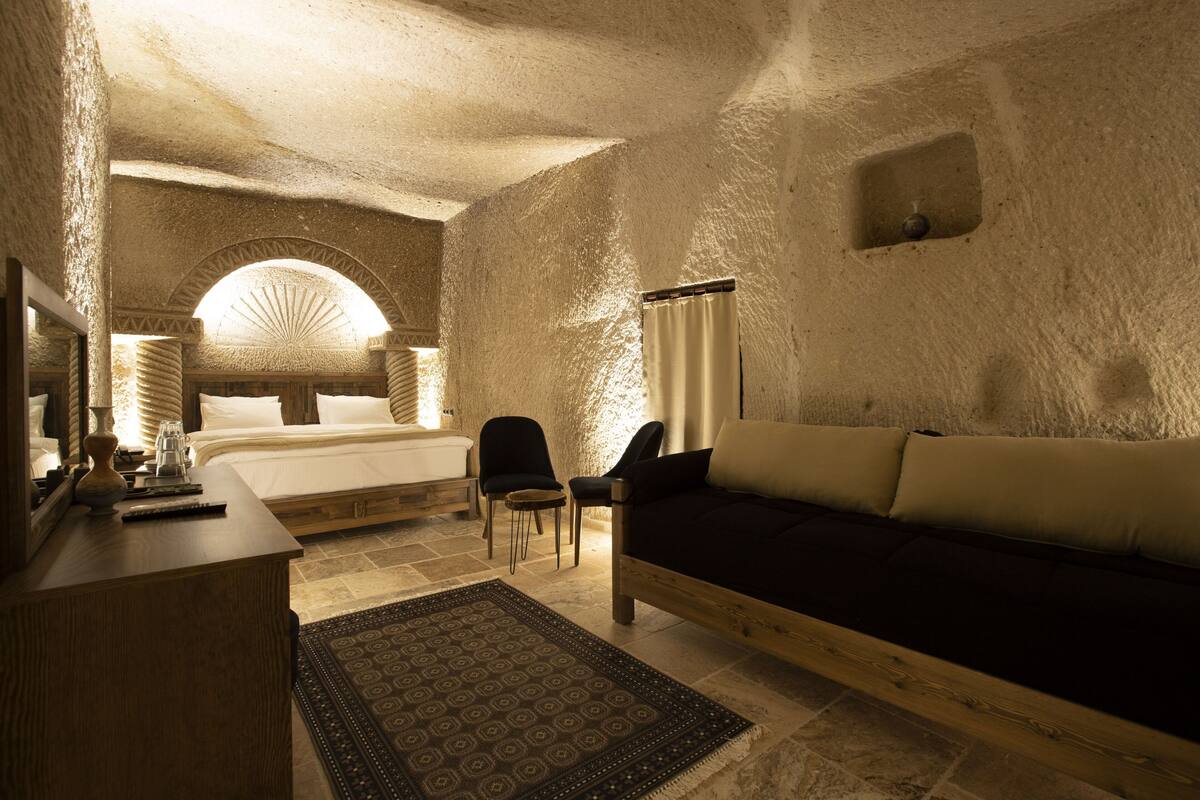A cozy room with a bed, a sofa, a desk, and a chair.