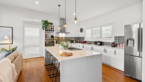 A modern kitchen with a central island, stainless steel appliances, and pendant lighting. - Bridge Water Views - Waterfront (Bonnie Doon)