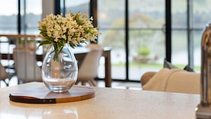 A clear view of a room with a large window, a vase with flowers on a table, and a view of the outdoors. - Bridge Water Views - Waterfront (Bonnie Doon)