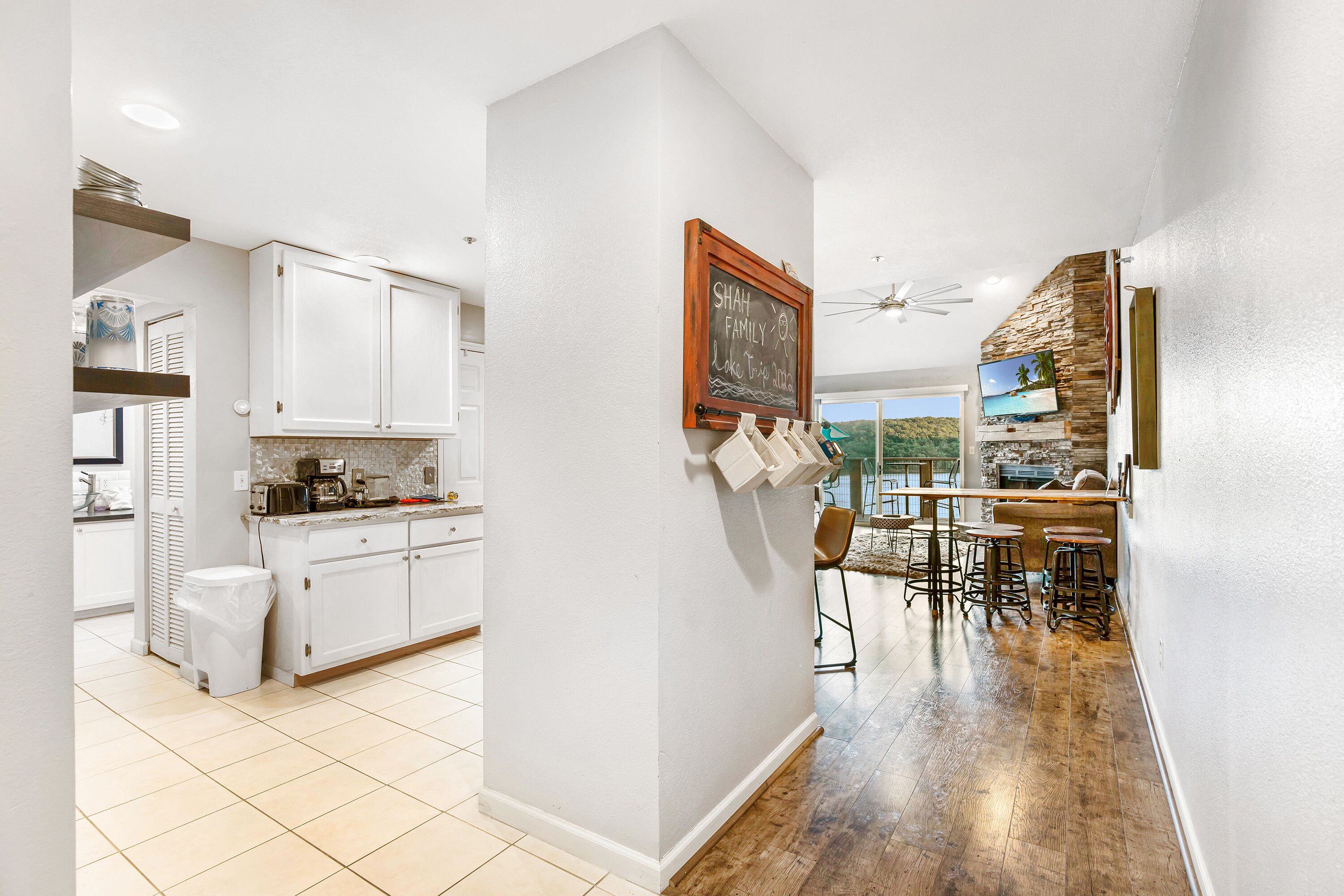 A kitchen with white cabinets, a chalkboard, and a dining area with stools.