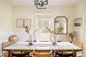 Enjoy meals in this traditional dining area with a long table for four, surrounded by elegant decor and natural light.