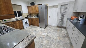 Una cocina con armarios de madera, un refrigerador de acero inoxidable, una lavadora y una estufa a gas.