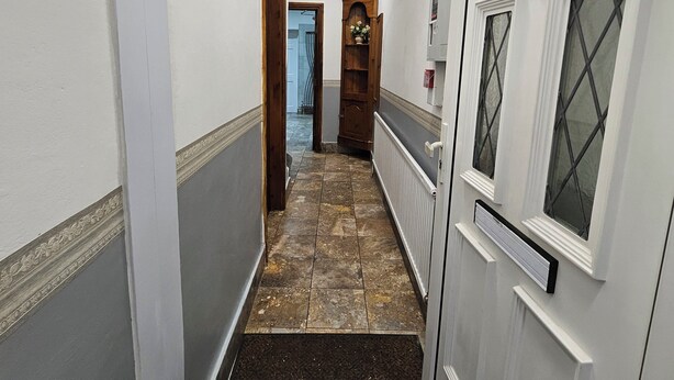 Un pasillo con suelo de baldosas, paredes blancas y una puerta con el número 13.