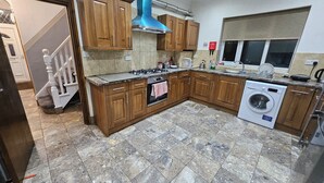 Una cocina con armarios de madera, estufa a gas, horno, lavadora y ventana con vistas.