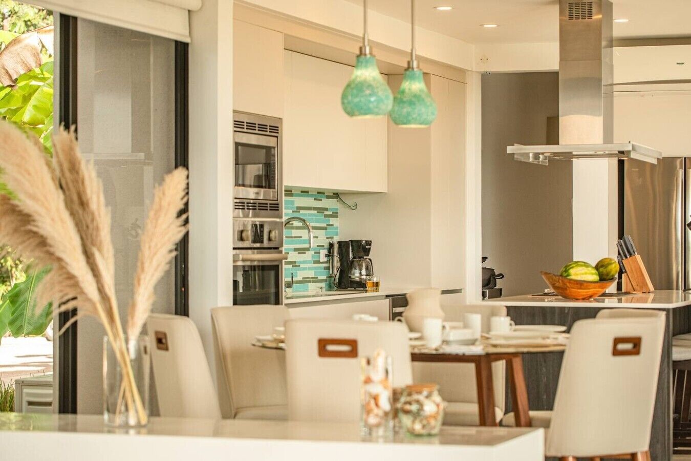 A modern kitchen with a built-in oven, a coffee machine, and a fruit bowl on the counter.