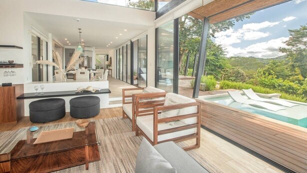 A modern interior with a dining area, kitchen, and a poolside lounge overlooking a lush landscape. - Casa La Reina, Private Jungle Villa (Tamarindo)