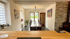A modern dining area with a wooden table, a black electronic device, and a view of a dining table set with chairs.