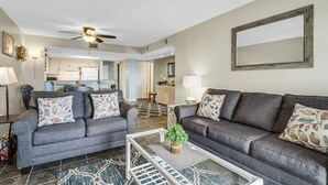 A living room with two grey sofas, a coffee table, and a ceiling fan. - Ocean View 3BR Suite: Beachside Escape (Myrtle Beach)