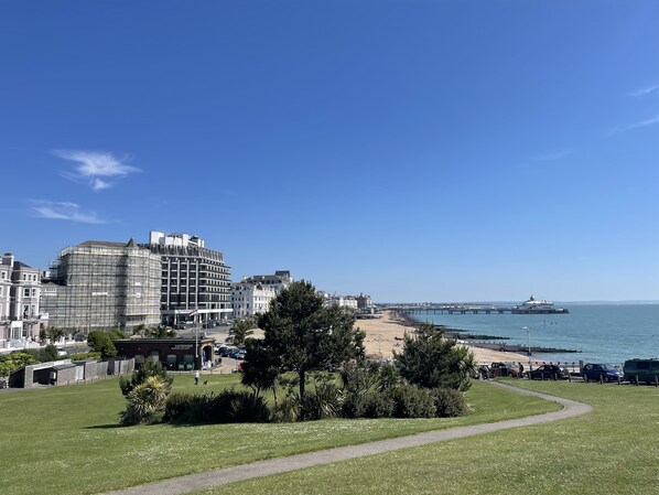 A coastal cityscape with a beach, a pier, and a large building under construction. - Spacious 2-bed Apartment With Free Parking (Eastbourne)