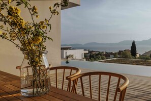 Una terraza de madera con vista despejada a una piscina y un paisaje lejano.