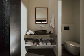 A modern bathroom with a large mirror, a bowl sink, and neatly rolled towels on shelves. - Villa Pelagia Summary (Paleros)