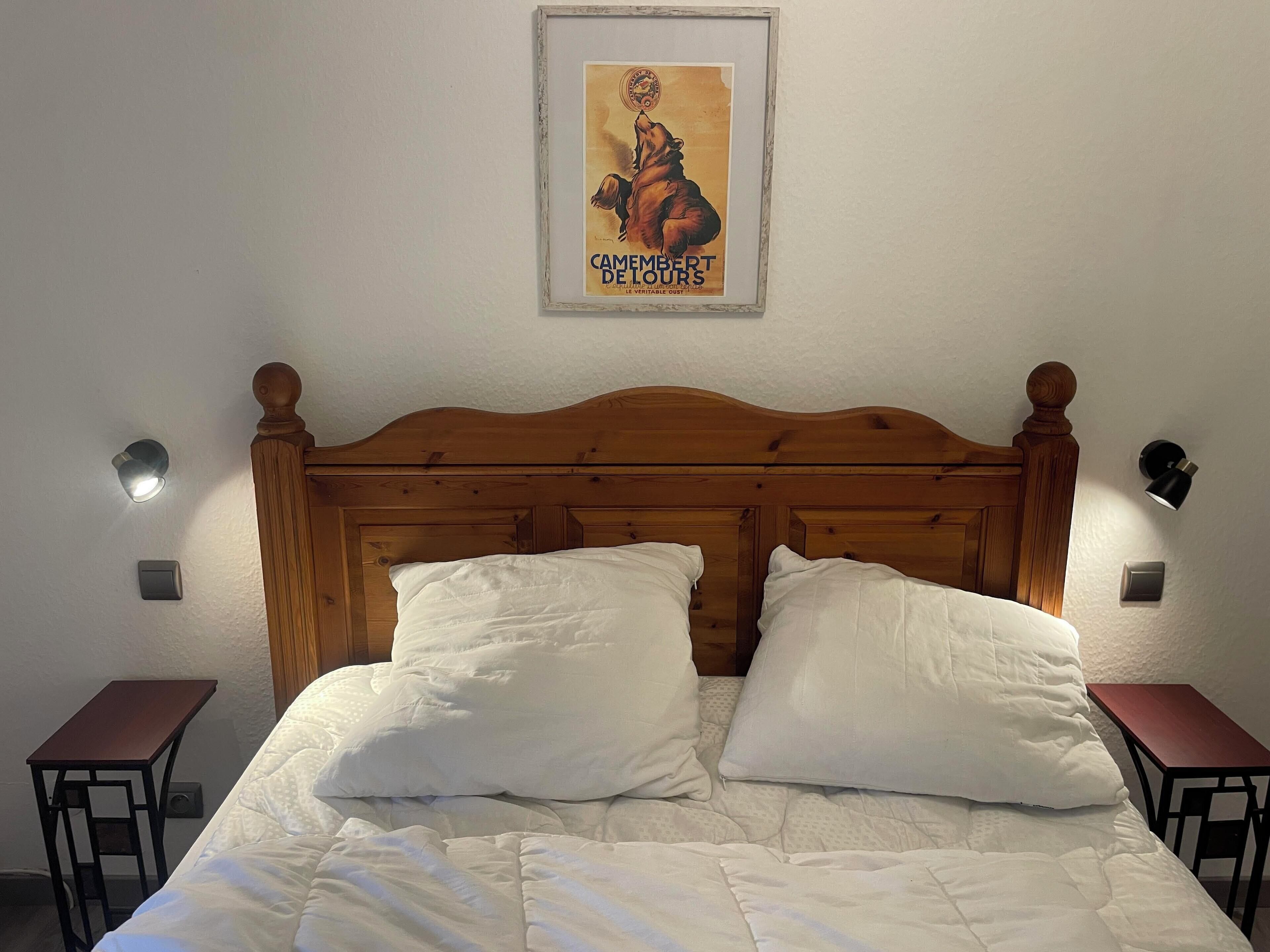 Un lit bien fait, avec une literie et des oreillers blancs, une tête de lit en bois et deux tables de chevet.