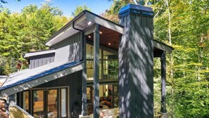 Une maison moderne dotée d’une grande baie vitrée, de fondations en pierre et d’une terrasse en bois.