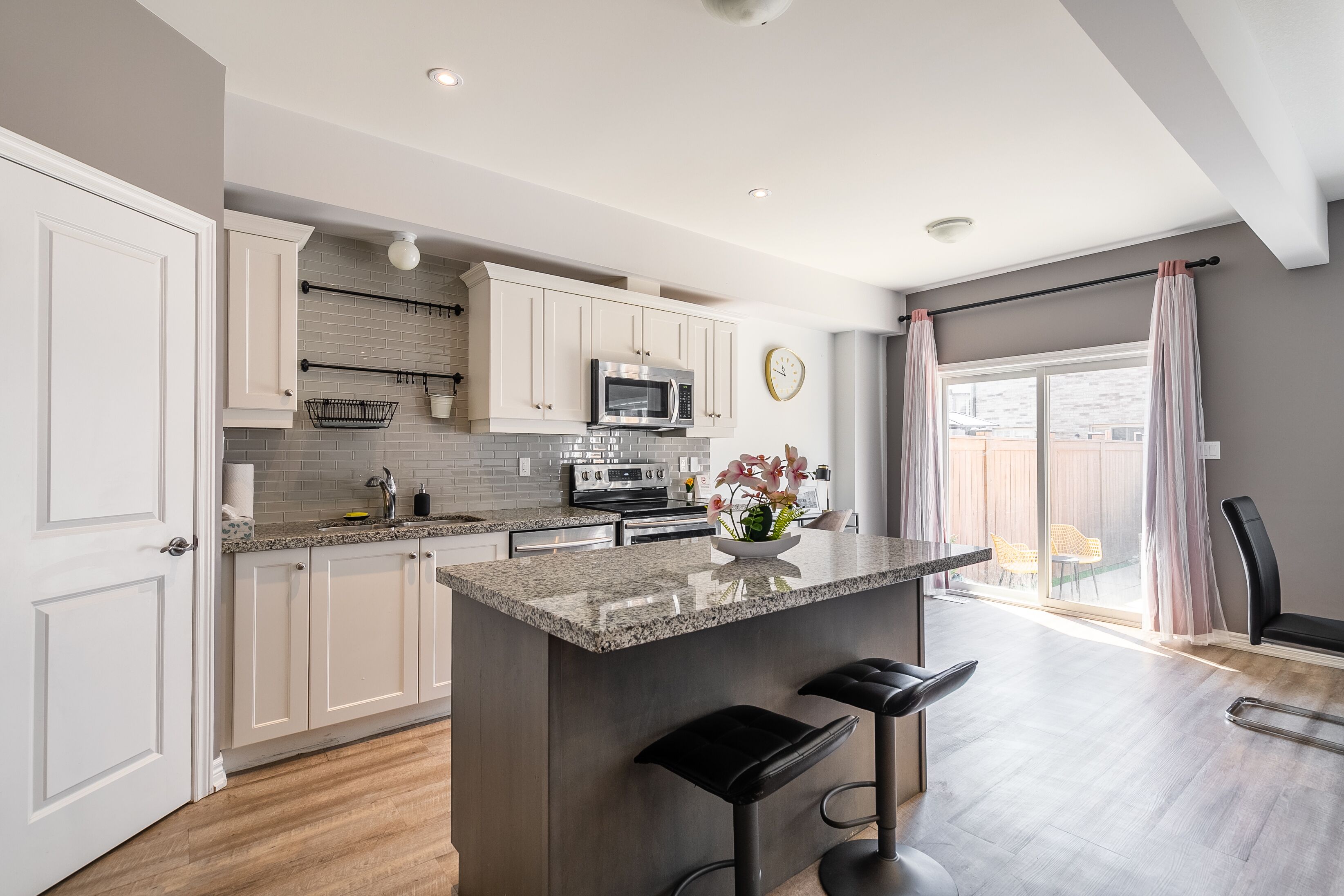 A modern kitchen with white cabinets, a granite countertop, and a central island with bar stools.