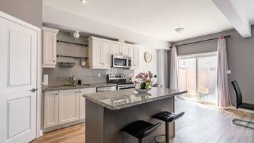 A modern kitchen with white cabinets, a granite countertop, and a central island with bar stools.